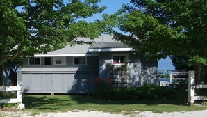 A single-story house with a garage, surrounded by trees and a gravel driveway. - Waterfront - secluded beachfront 
Last Min Discount for week of August 29-Sept 5 (Portsmouth)