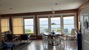 A spacious room with a large dining table, several chairs, a sofa, and a view of the sea through large windows. - Waterfront - secluded beachfront 
Last Min Discount for week of August 29-Sept 5 (Portsmouth)
