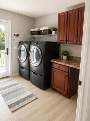 Une cuisine compacte avec deux appareils électroménagers noirs, des meubles en bois, un petit plan de travail et un tapis à rayures.