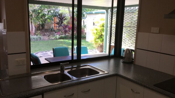 Una cocina con dos fregaderos, una encimera y vistas a un jardín con sillas y una mesa.