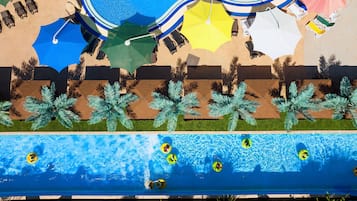 Zona de piscina en la azotea con varias sombrillas, sillas de descanso y palmeras.
