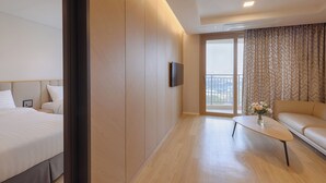 Une chambre d’hôtel moderne, équipée d’un lit, d’un canapé, d’une table basse et d’un téléviseur fixé au mur.