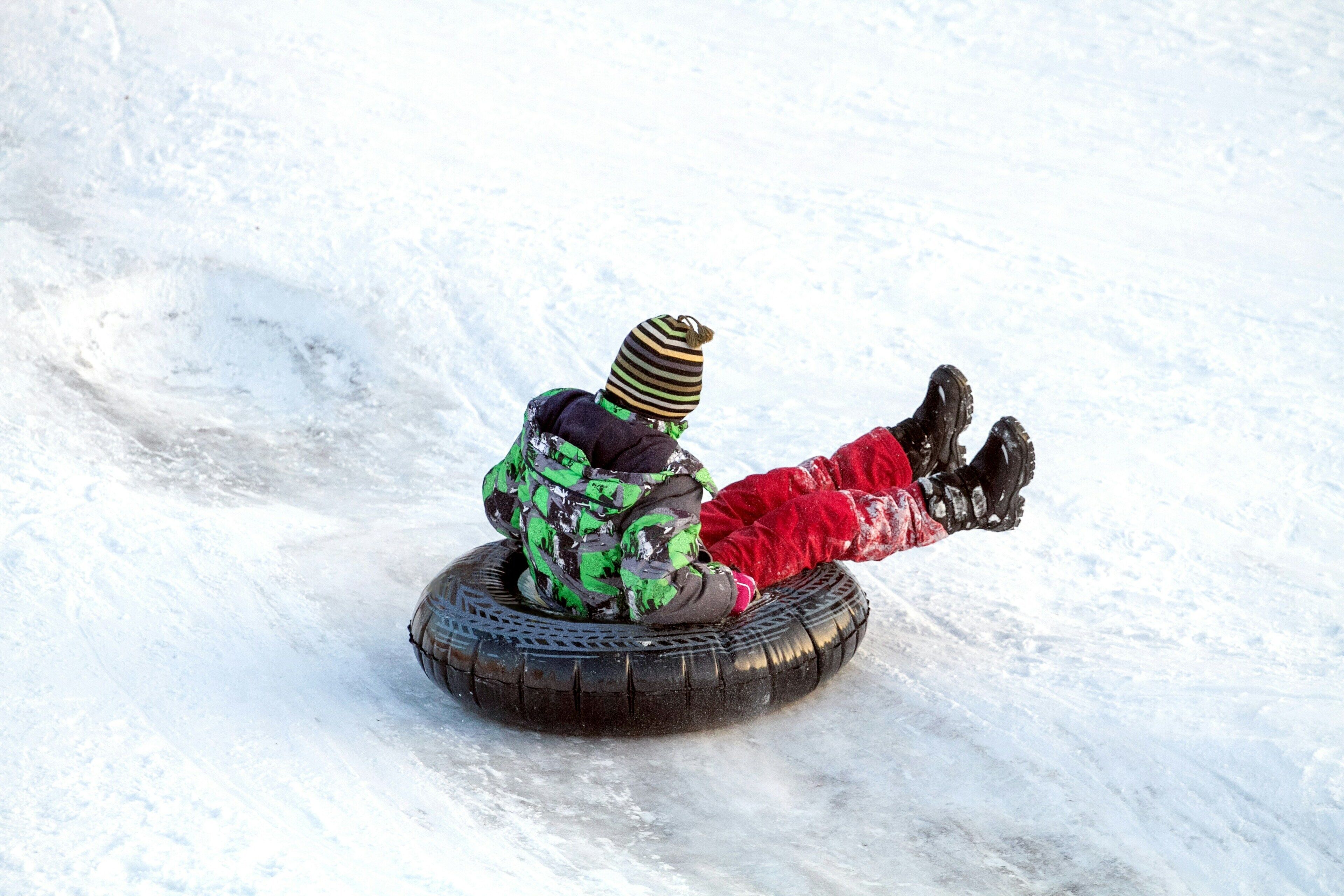 A person sledding down a snowy slope on a large tire.