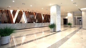Un hall d’entrée moderne avec un comptoir de réception en marbre, des plantes en pot et un sol propre et ciré.
