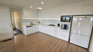 A modern kitchen with white cabinets, a built-in oven, and a refrigerator with a "No Smoking" sign. - STUNNING VIEWS, 6 bedrooms, 12 people, fireplace, early check-in, late check-out (Mount Victoria)
