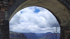 An arched stone structure with a concrete pathway leading to a fenced area with a view of mountains. - STUNNING VIEWS, 6 bedrooms, 12 people, fireplace, early check-in, late check-out (Mount Victoria)