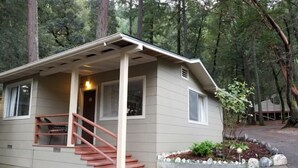A small, single-story cabin with a covered porch and a staircase leading to the entrance. - China Creek Cottages (Willow Creek)