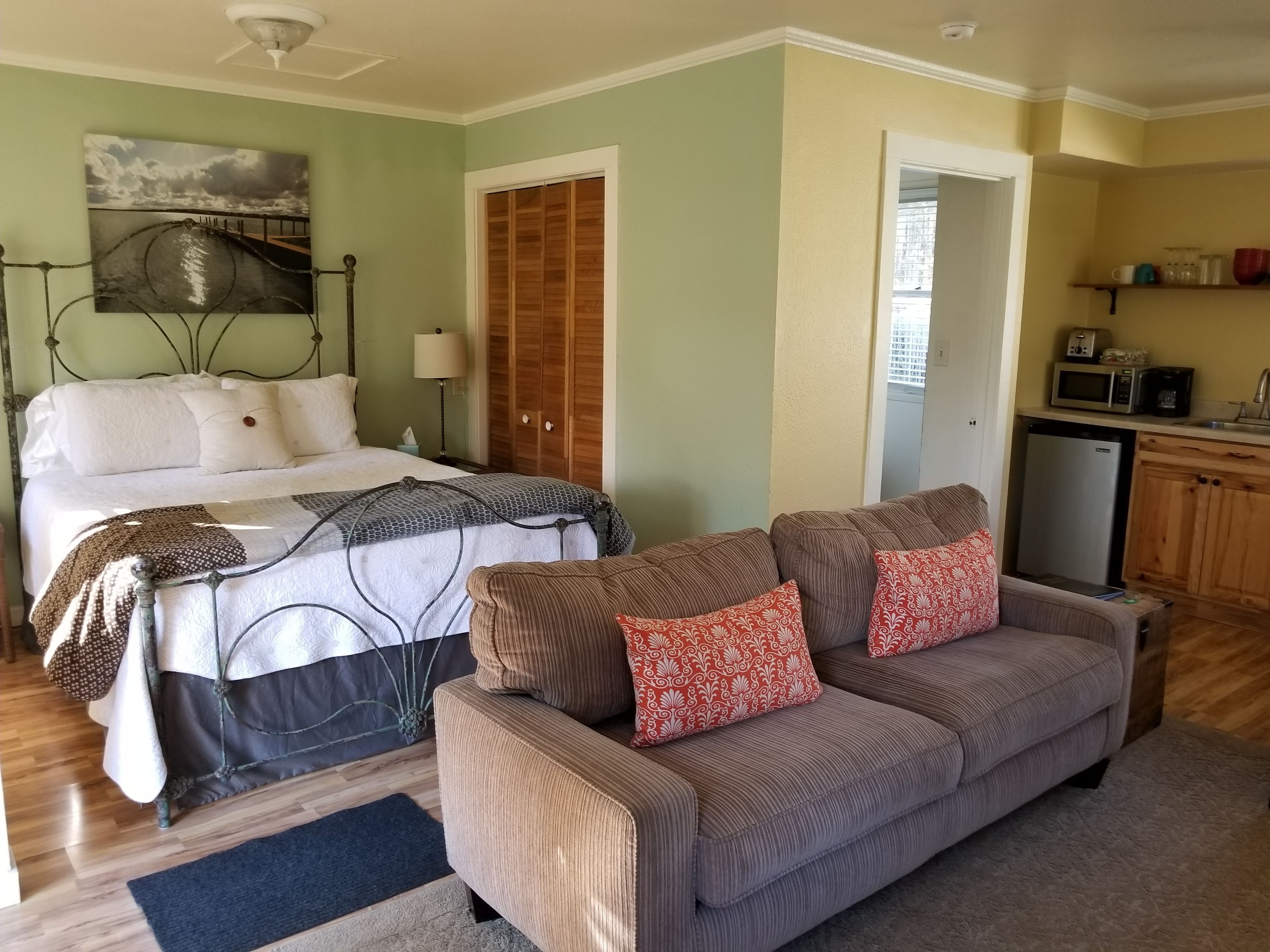 A bedroom with a bed, bedside table, lamp, and a painting on the wall.