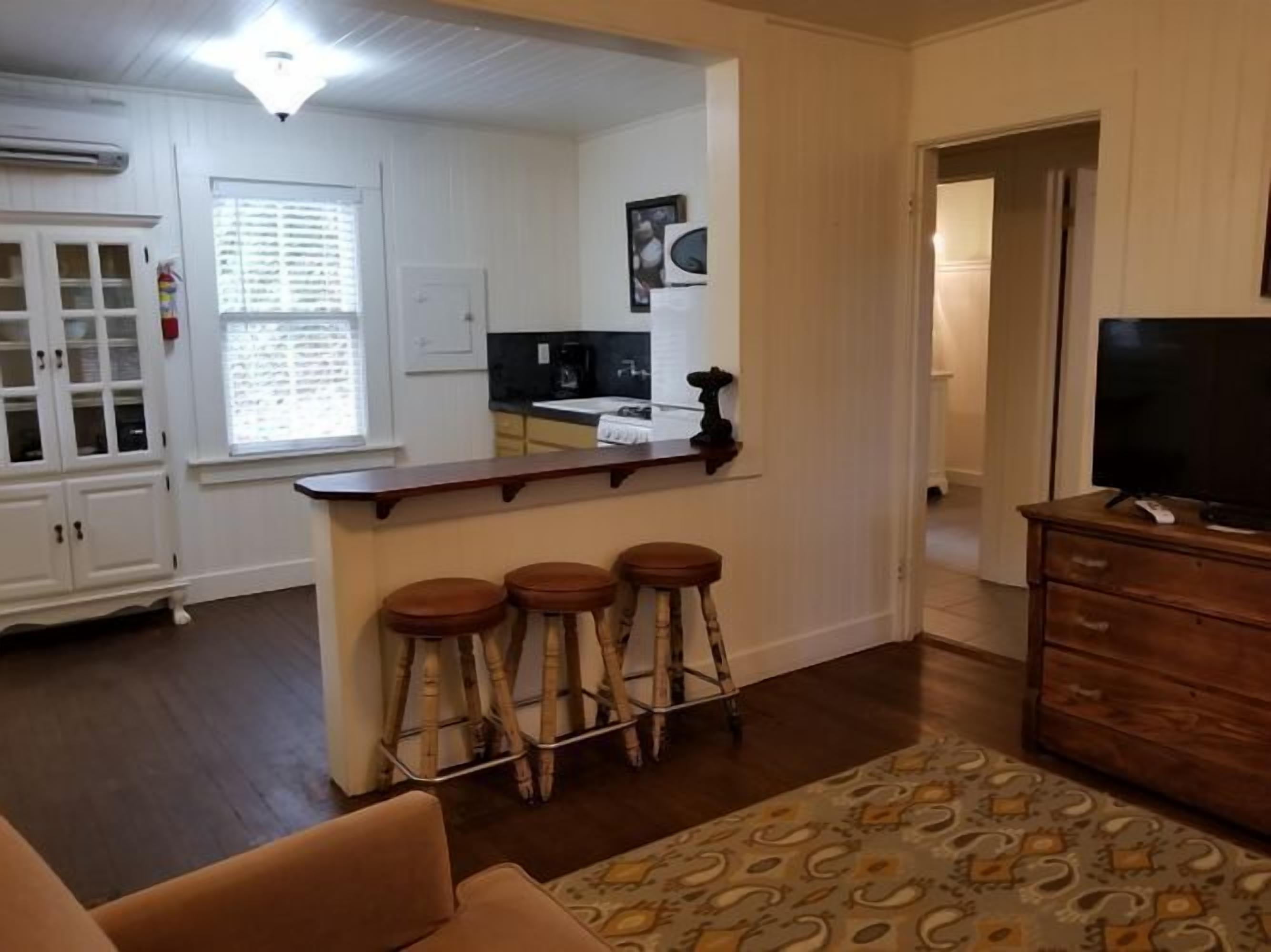 Una sala de estar con una zona de bar, un televisor y una alfombra estampada.