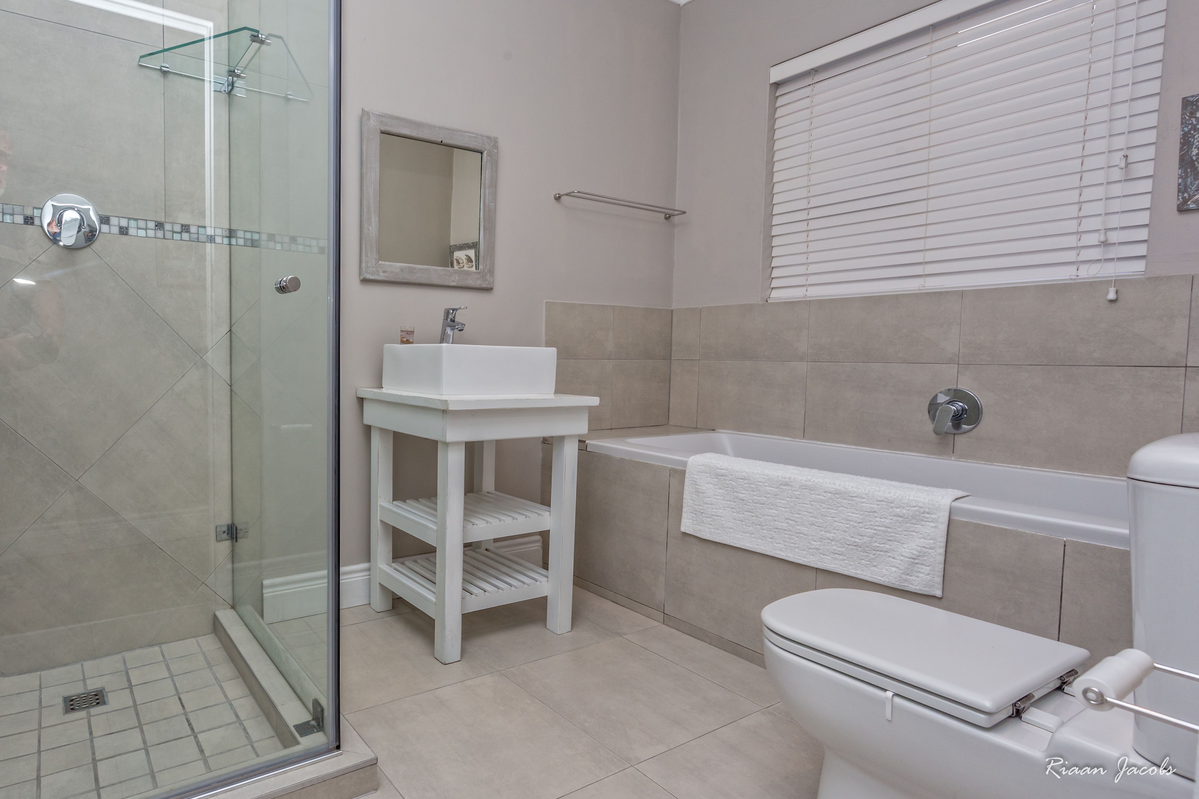A modern bathroom with a glass-enclosed shower, a white sink, and a bathtub.