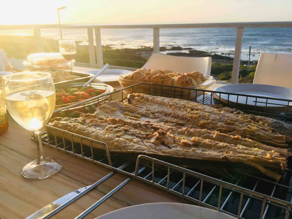 A seafood grill with grilled fish and bread on a table with a view of the ocean.
