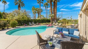 A backyard with a swimming pool, lounge chairs, a sofa, and tall palm trees. - Private Pool Resort Home - Walk to Music Festivals Polo Grounds (Indio)