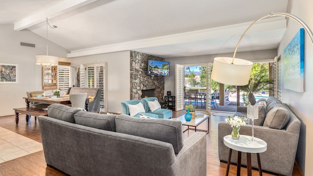 A spacious living area with a grey sofa set, a coffee table, and a TV mounted on the wall. - Private Pool Resort Home - Walk to Music Festivals Polo Grounds (Indio)