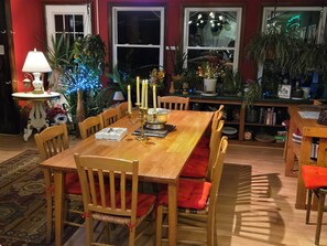Un coin repas avec une table en bois, des chaises, un chandelier et une plante en pot.