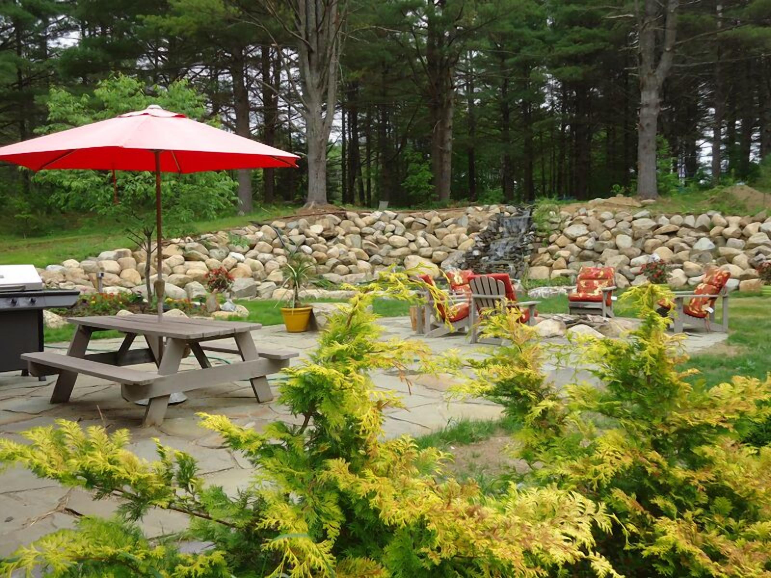 A patio area with a picnic table, outdoor seating, and a stone wall.