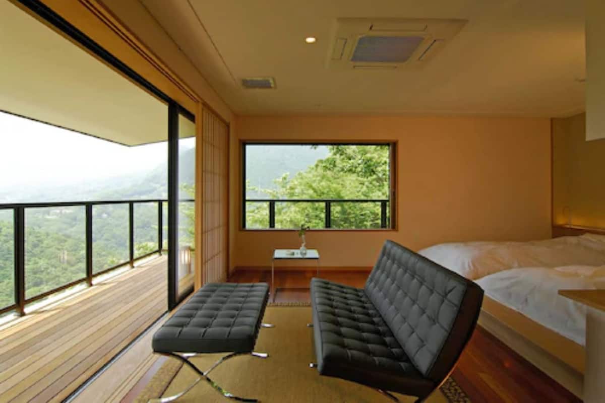 Un dormitorio moderno con una ventana grande, una cama, un sofá y una mesita.