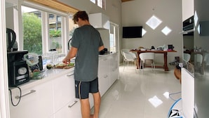 Une cuisine moderne avec des meubles blancs, un plafond en bois et un coin repas comprenant une table et des chaises.