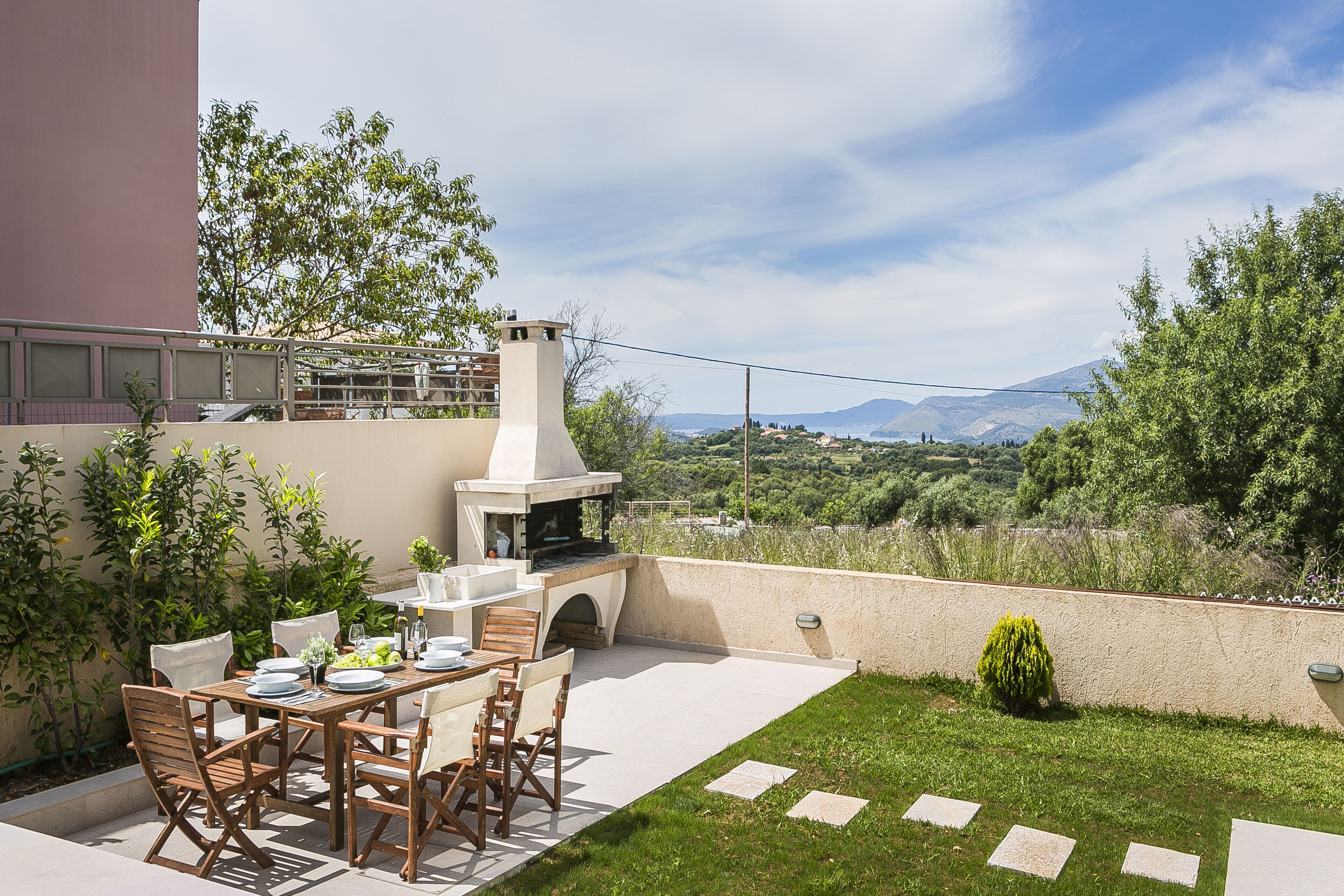 An outdoor patio with a dining table, chairs, and a barbecue grill.