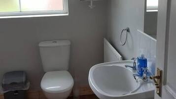 Un baño con inodoro, lavamanos, ventana y radiador.