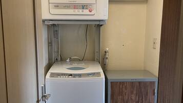 Ein kleiner Waschraum mit einer Waschmaschine mit Frontlader, einem Trockner und einem Schrank.