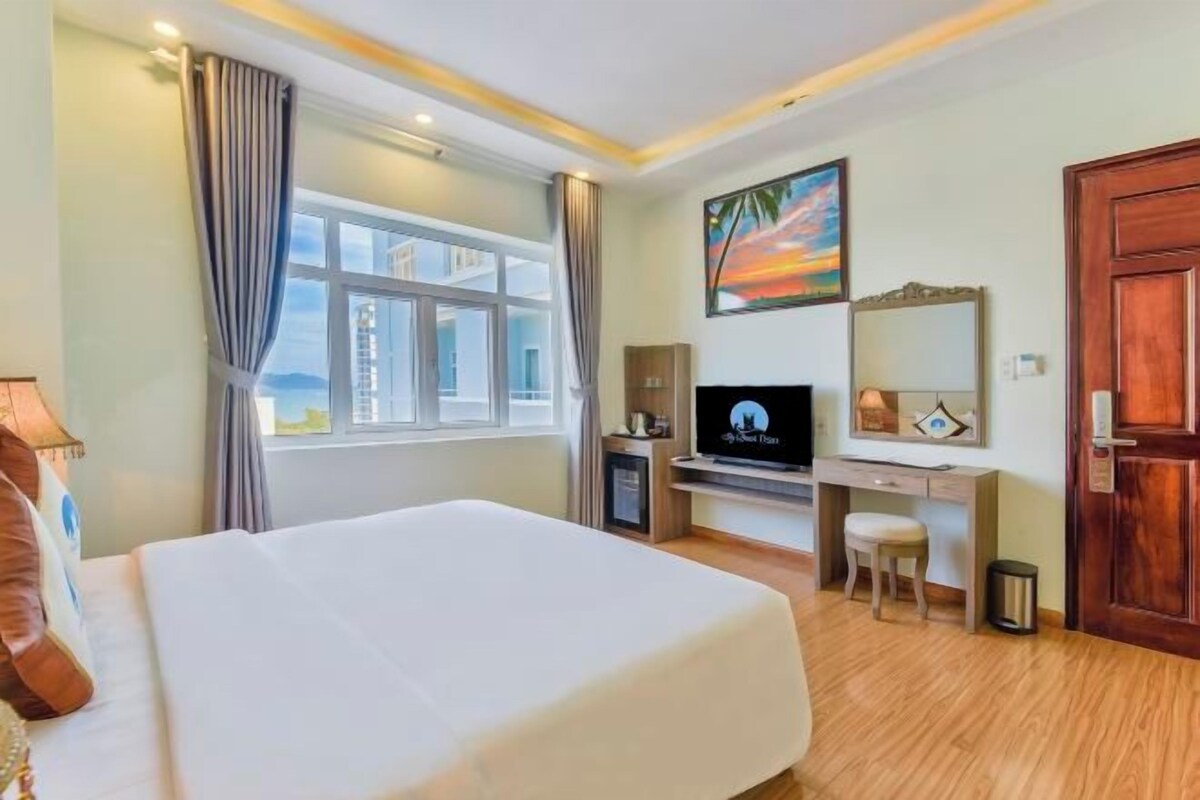 Ein Hotelzimmer mit Bett, Schreibtisch, Fernseher und einem Fenster mit Vorhängen.