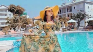 A person in a tropical print dress and wide-brimmed hat by a pool with buildings in the background. - Sky Beach D20 Nha Trang Hotel (Nha Trang)