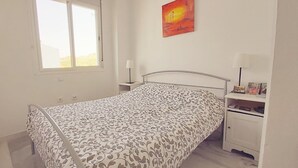Ein Schlafzimmer mit Bett, Nachttisch, Lampe und einem Bild an der Wand.