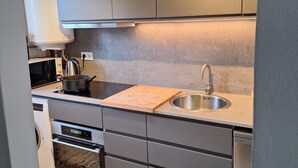 Eine moderne Küche mit grauen Schränken, einer Edelstahl-Spüle und einem eingebauten Backofen.