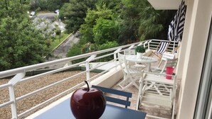 Un balcón con una mesa, sillas y una planta en maceta.
