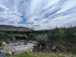 A patio with outdoor seating, a stone pathway, and a view of a hill.