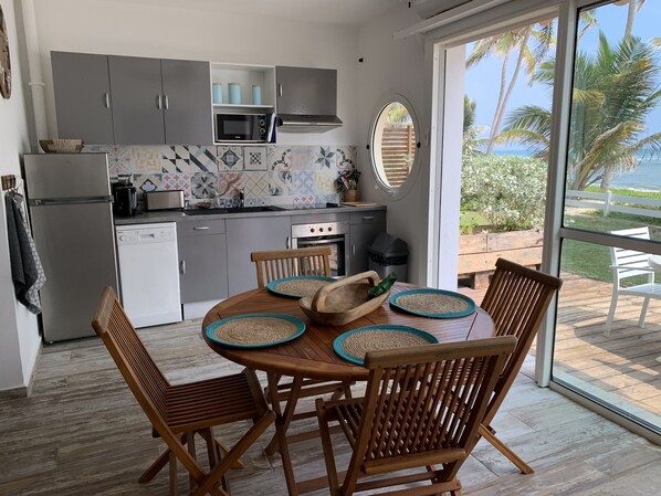 A modern kitchen with grey cabinets, a microwave, and a stove. There is a dining area with wooden chairs and a table.