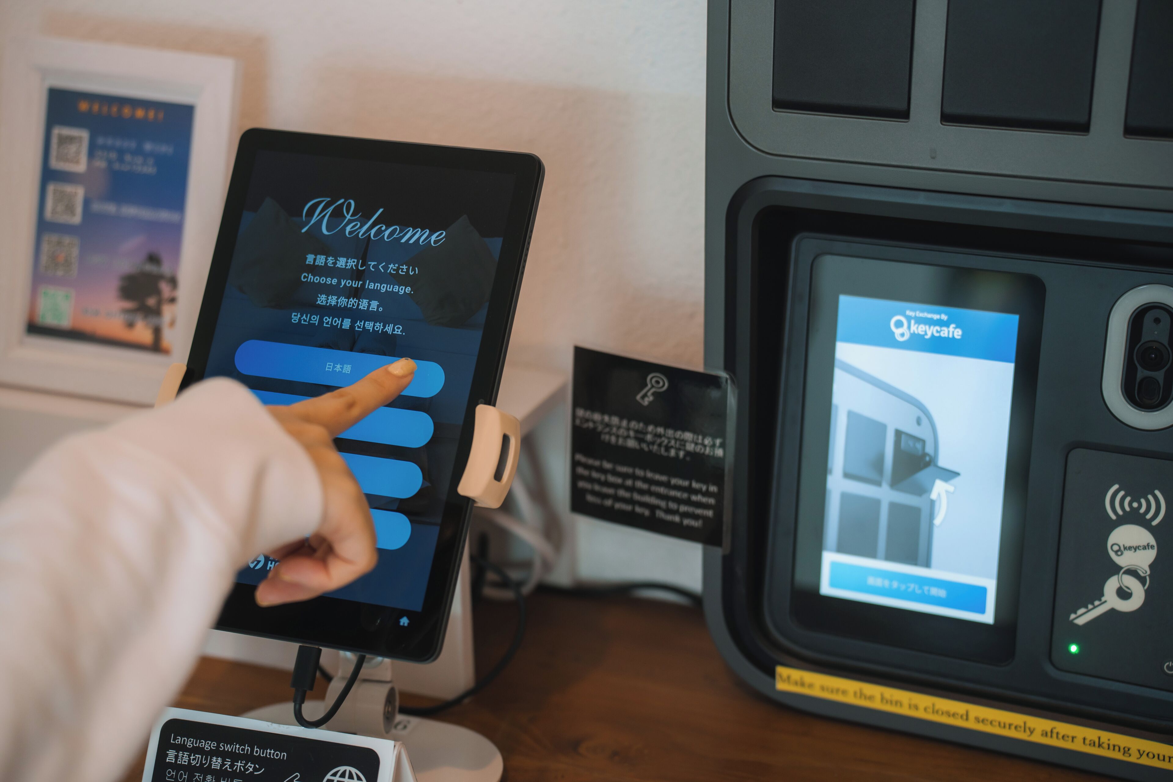 A tablet displaying a welcome screen with language options, a QR code, and a sign for a language switch button.