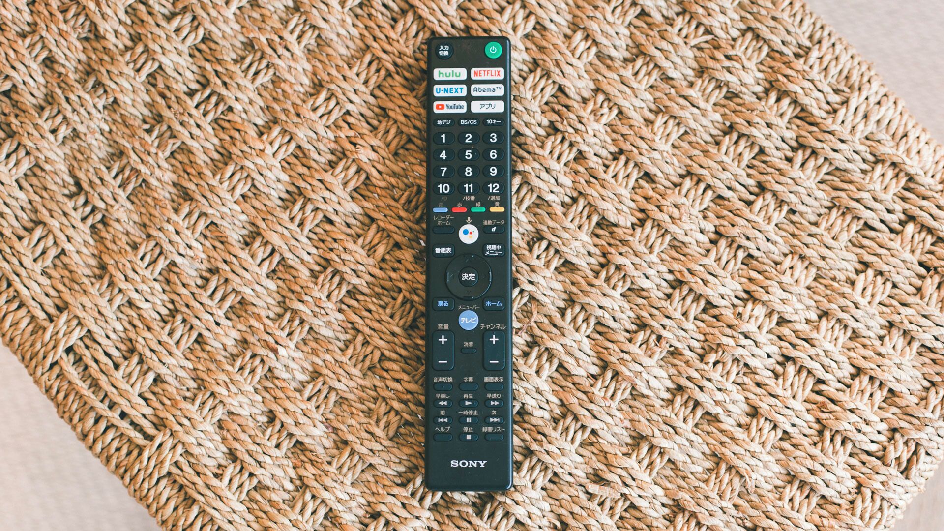 Un control remoto negro Sony sobre un tapete tejido.