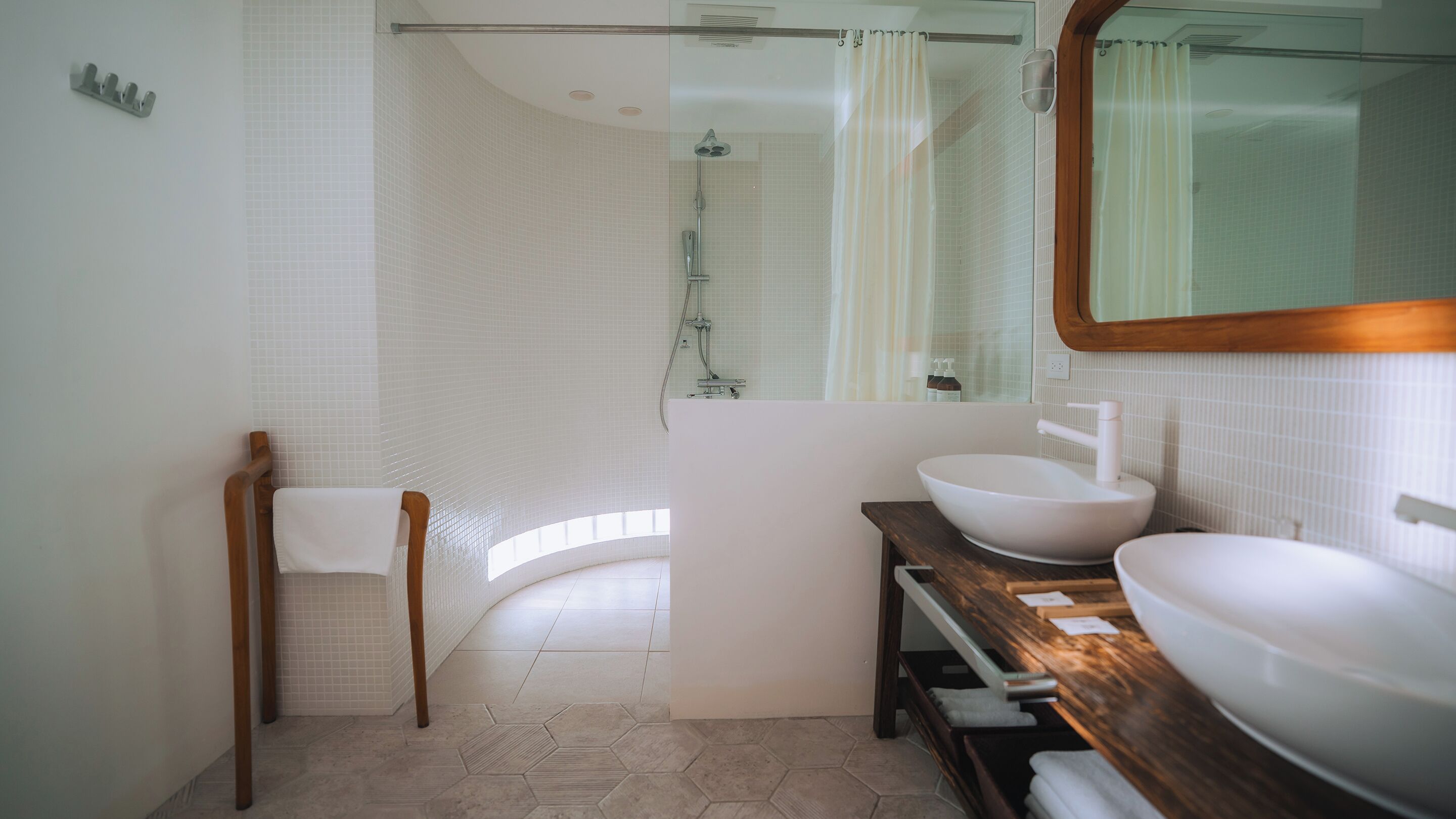 A modern bathroom with a wooden vanity, a large mirror, and a shower area.