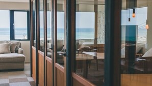 Ein modernes Interieur mit kariertem Boden, einer Couch, einem Essbereich und Meerblick durch große Fenster.