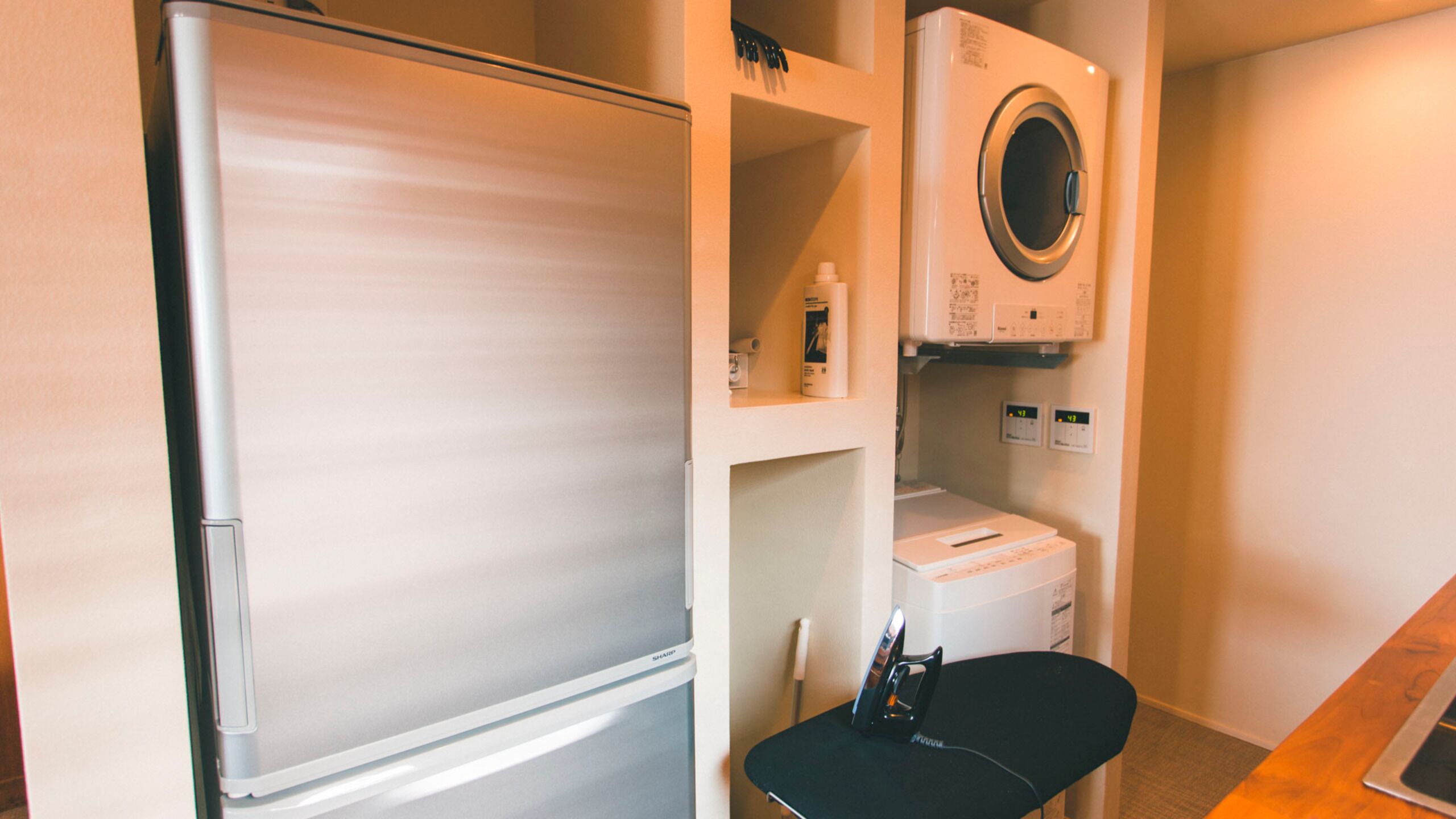 A compact room with a refrigerator, a washing machine, and a chair.