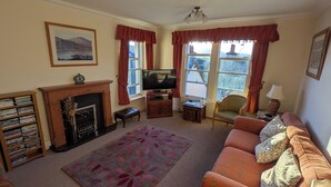 A living room with a fireplace, television, sofa, and a bookshelf.
