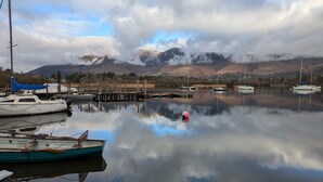 A calm lake with boats docked, a dock, and mountains in the background.