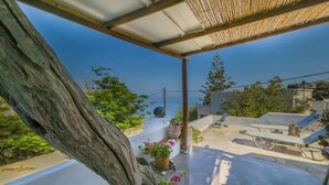 A rooftop terrace with a pergola, potted plants, and outdoor furniture.