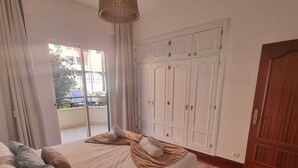 A bedroom with a large bed, a wooden door, and a wardrobe. - Terrace Garden Apartment  (Funchal)