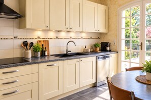 Una cocina con lavavajillas integrado, cafetera y ventana con vistas al verdor.