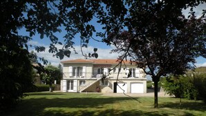 A two-story house with a red-tiled roof, a front staircase, and a garage.
