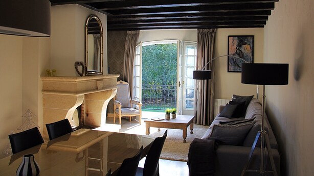 A living room with a fireplace, a sofa, a coffee table, and a dining area with chairs and a table.
