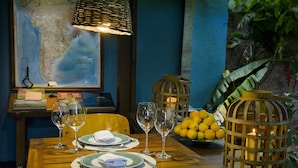 A dining table set with plates, cutlery, and wine glasses, a candle in a lantern, and a fruit bowl. - Secret garden iguazu (Puerto Iguazú)