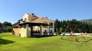 Et toetagers hus med terrasse, gyngestativ og swimmingpool.