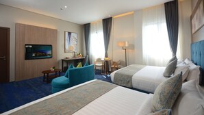 A hotel room with two beds, a desk with a chair, a TV, and a small table with a lamp. - Blue Lotus Hotel Davao (Davao)