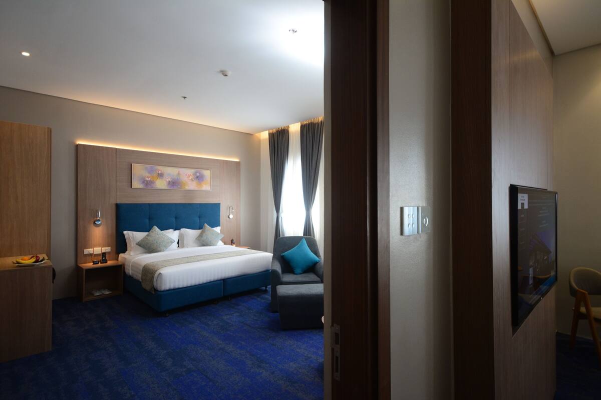 A modern hotel room with a large bed, a desk, and a television.
