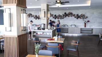 Restaurante moderno com área de serviço central, mesas e parede decorativa.