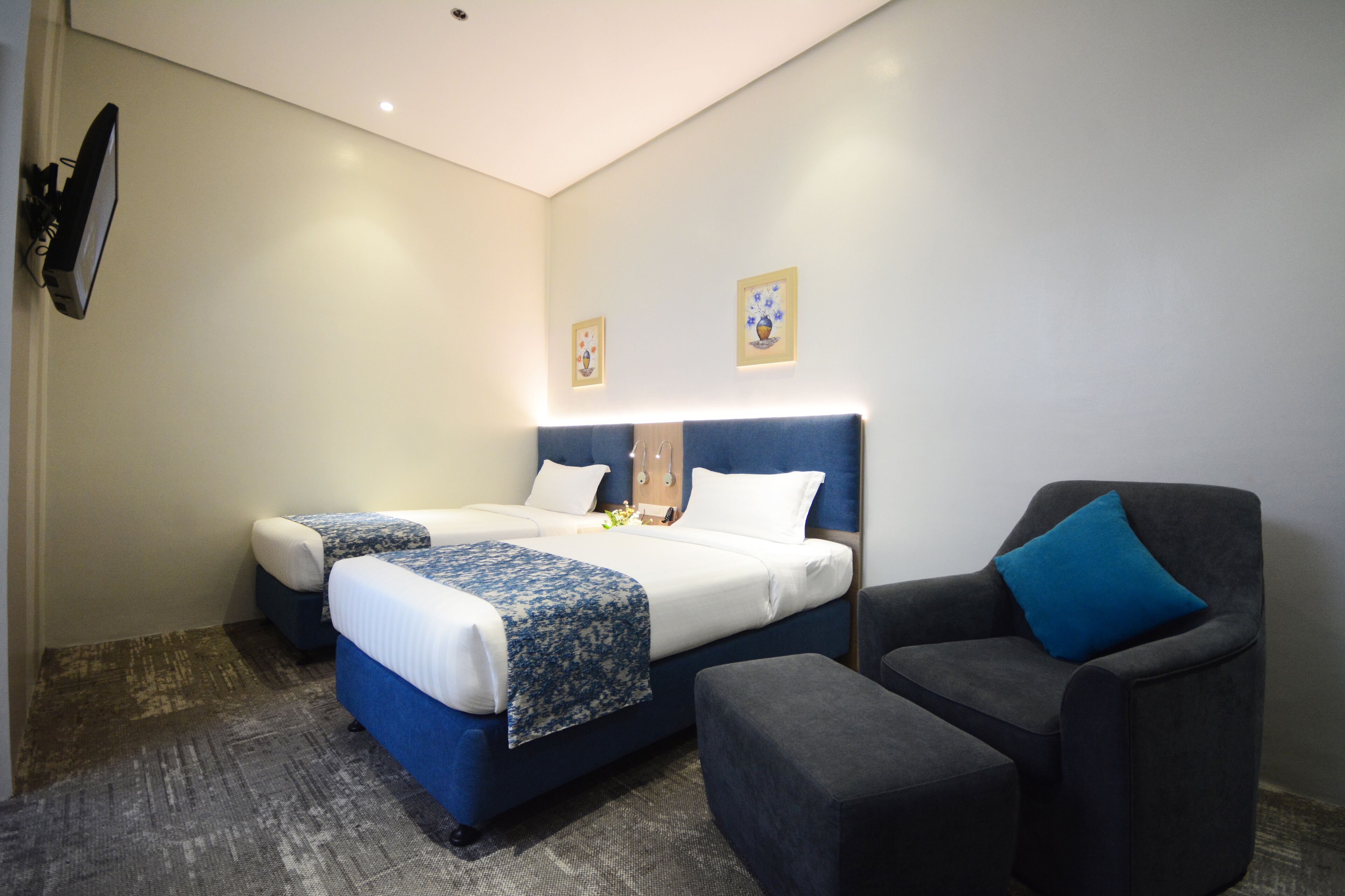 Una habitación de hotel con una cama, una silla y un televisor de pantalla plana montado en la pared.