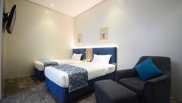 A hotel room with a bed, a chair, and a flat-screen TV mounted on the wall.